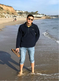 Jacob Duenas III standing on a beach, wearing a jacket.