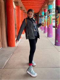 Melanie Mandell posing between columns, wearing jacket.
